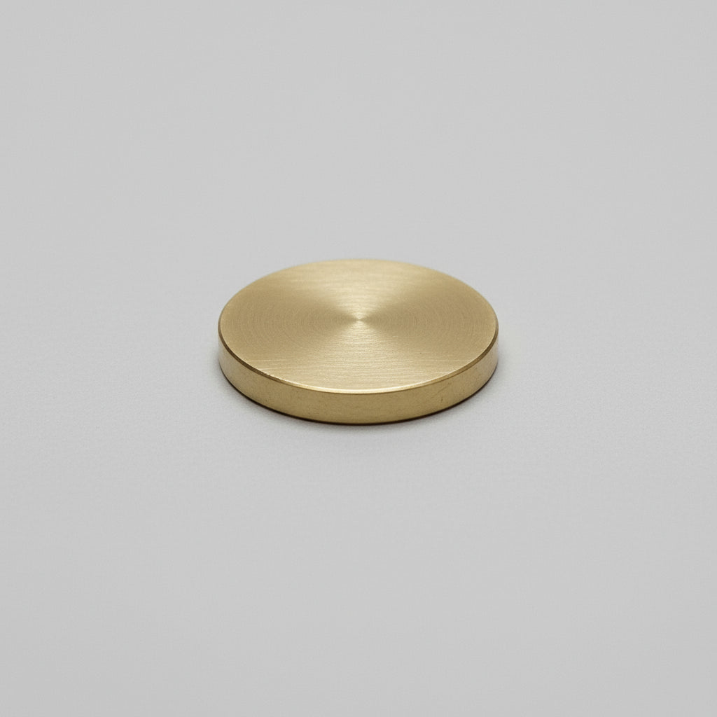 Hand holding a gold-colored object against a wooden surface