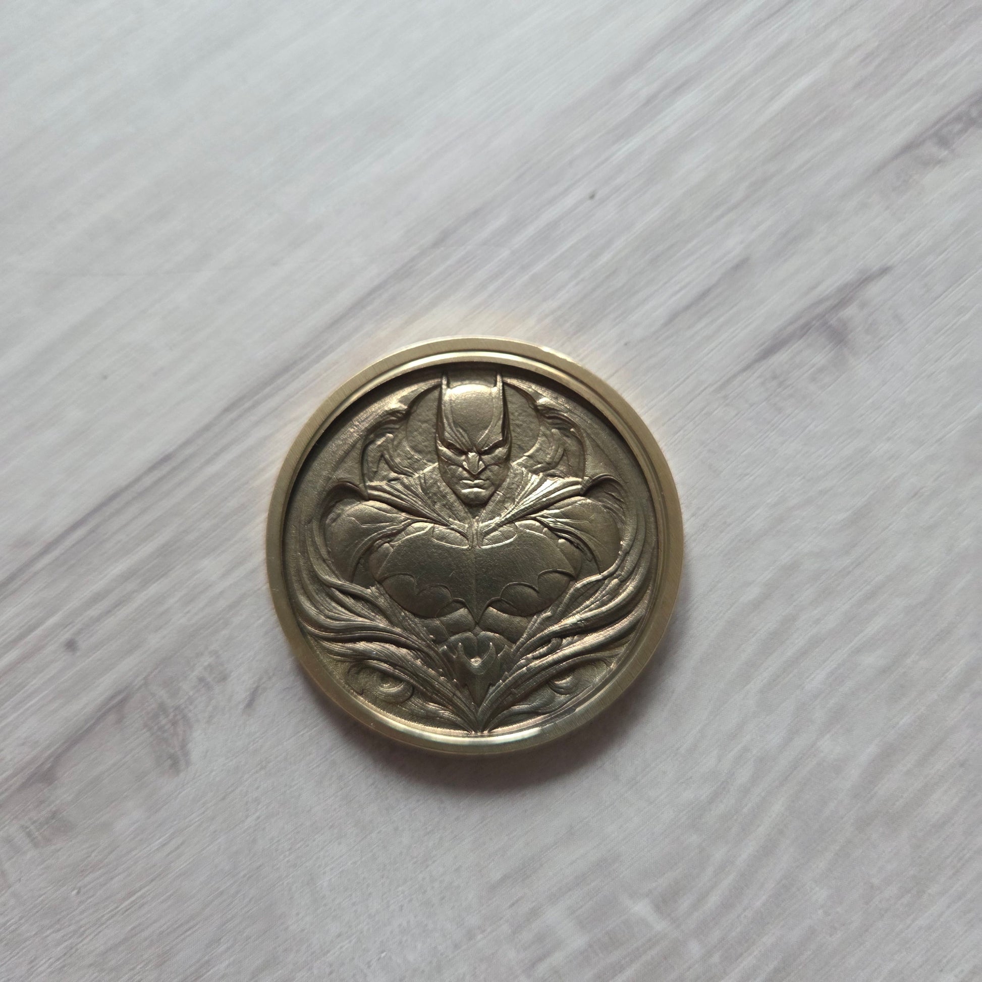 Decorative metal button with intricate design on a light wooden surface