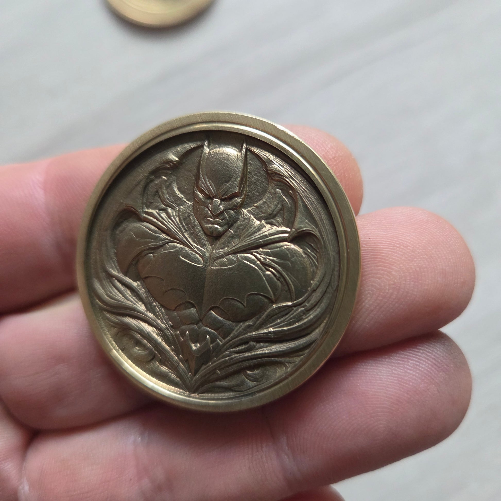 Brass decorative button held in a hand with a plain background