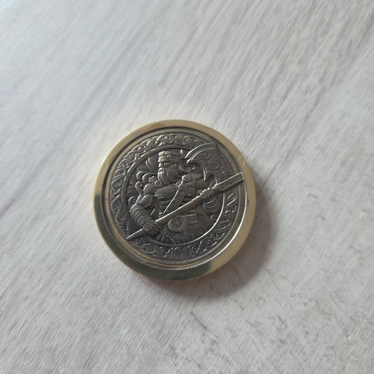 Silver coin with intricate design on a light gray surface