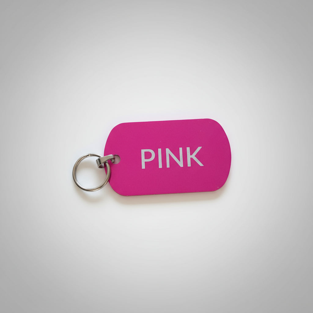 Pink keychain tag with 'PINK' text on a gray wooden surface