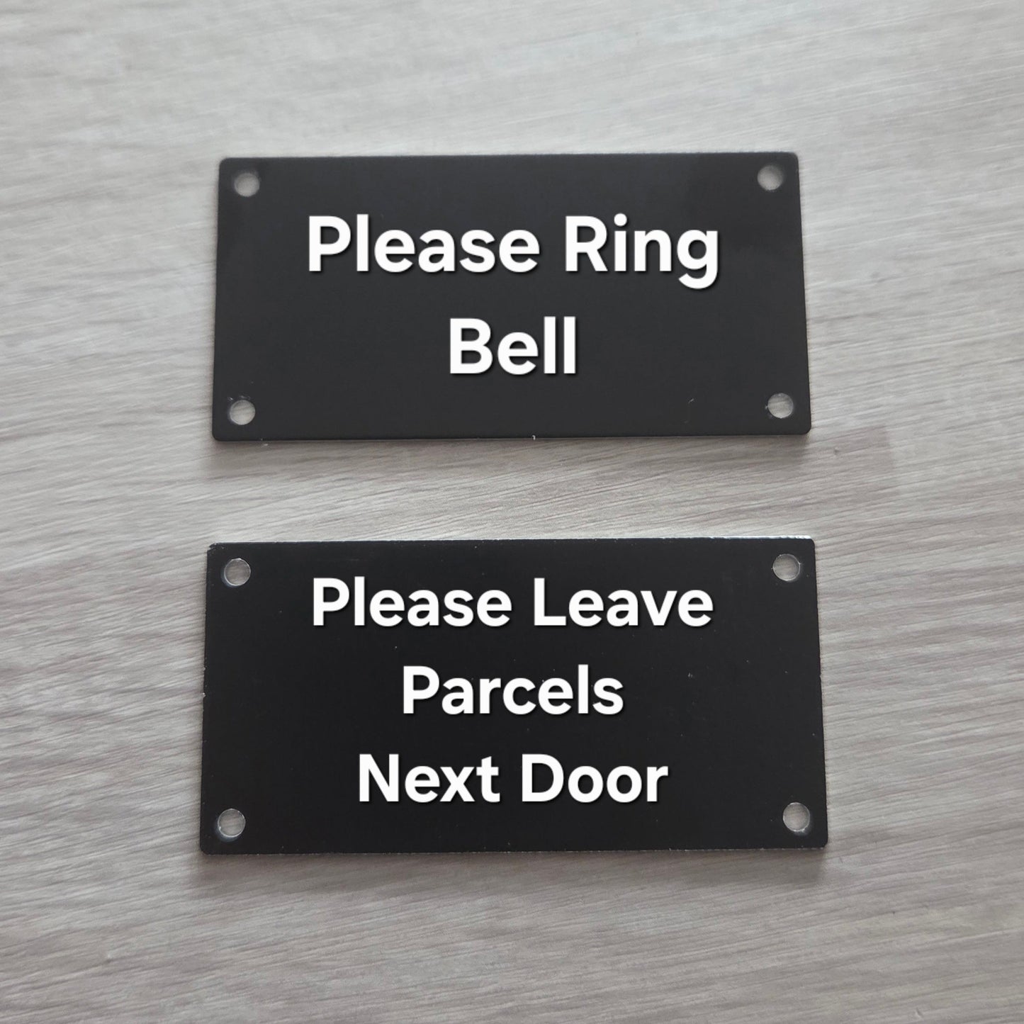 Two black signs on a door with white text.