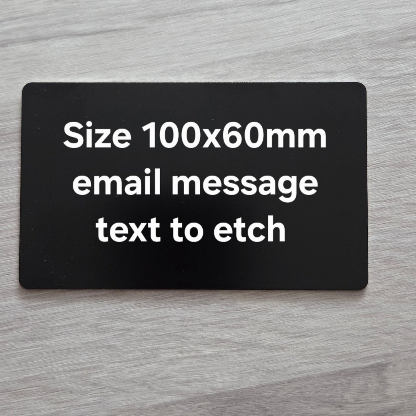 Black rectangular card with text on a gray wooden surface