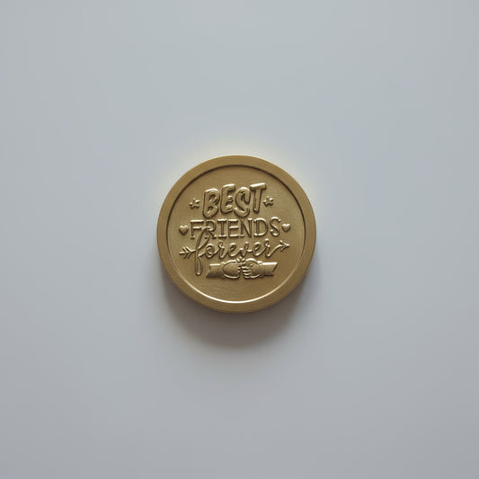 Bronze coin with text on a light wooden surface