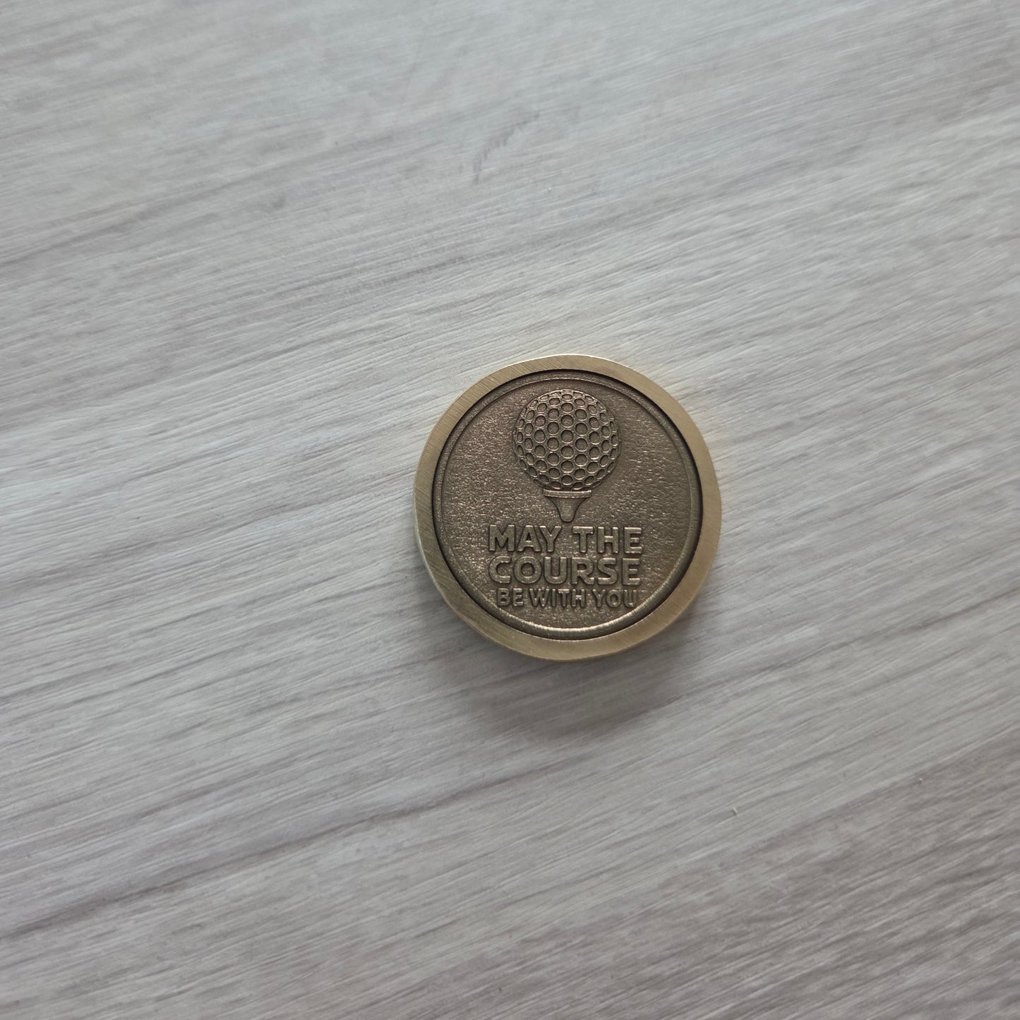 Round metallic object with embossed design on a light wooden surface