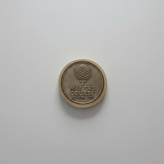 Round metallic object with embossed design on a light wooden surface