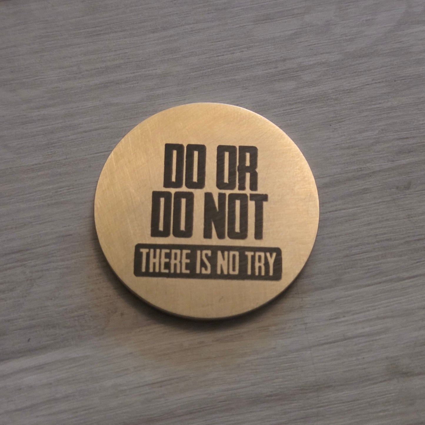 Round wooden coaster with engraved text on a wooden surface