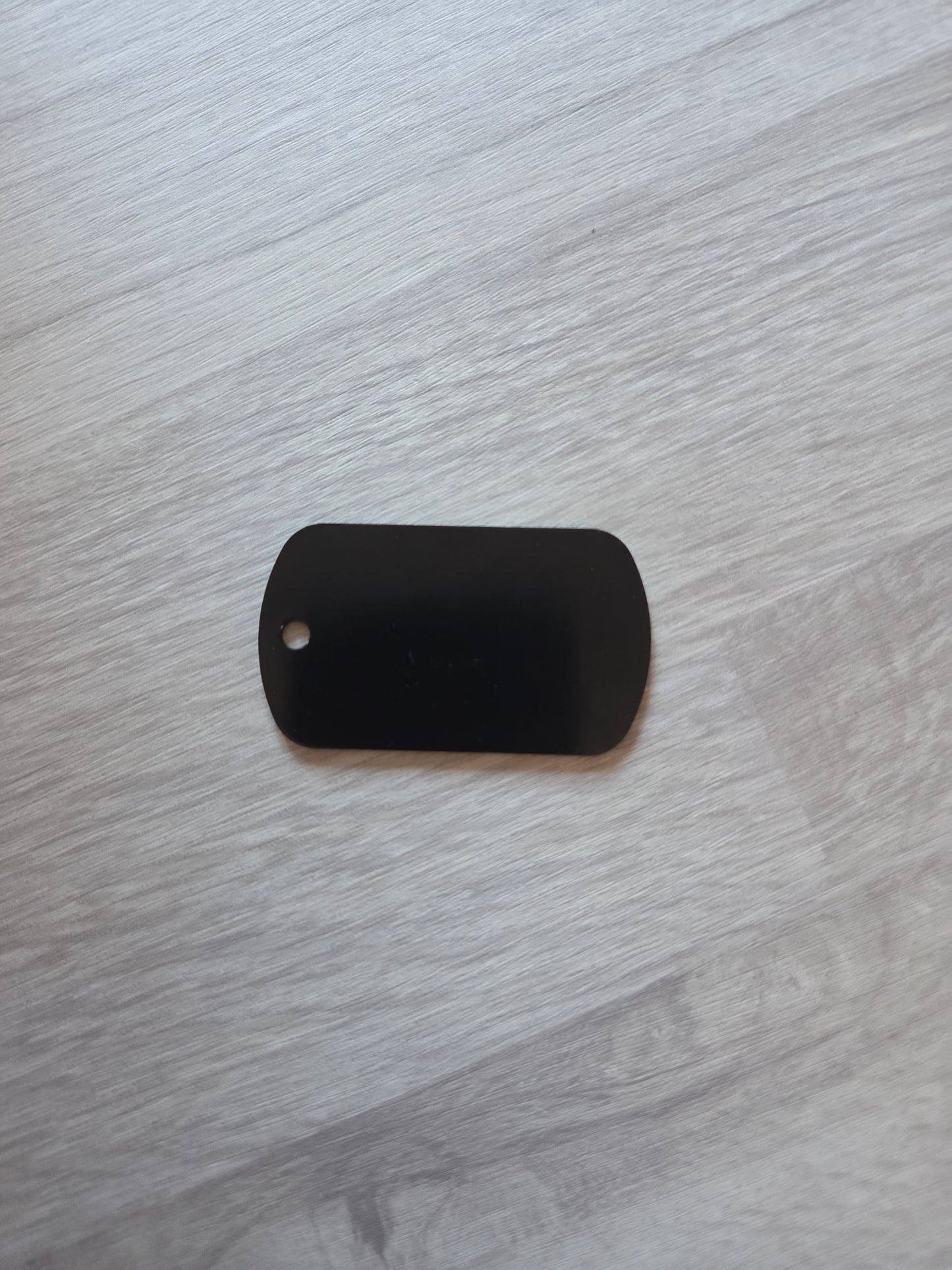 Black rectangular object with a small hole on a gray wooden surface
