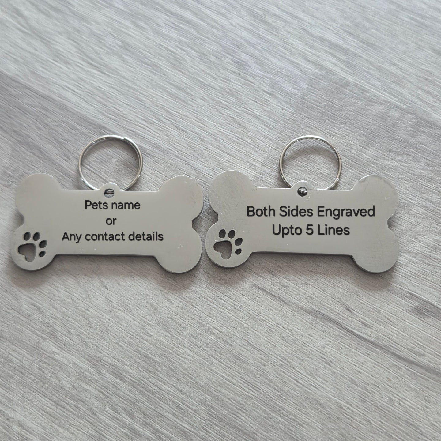 Two bone-shaped pet tags on a gray surface