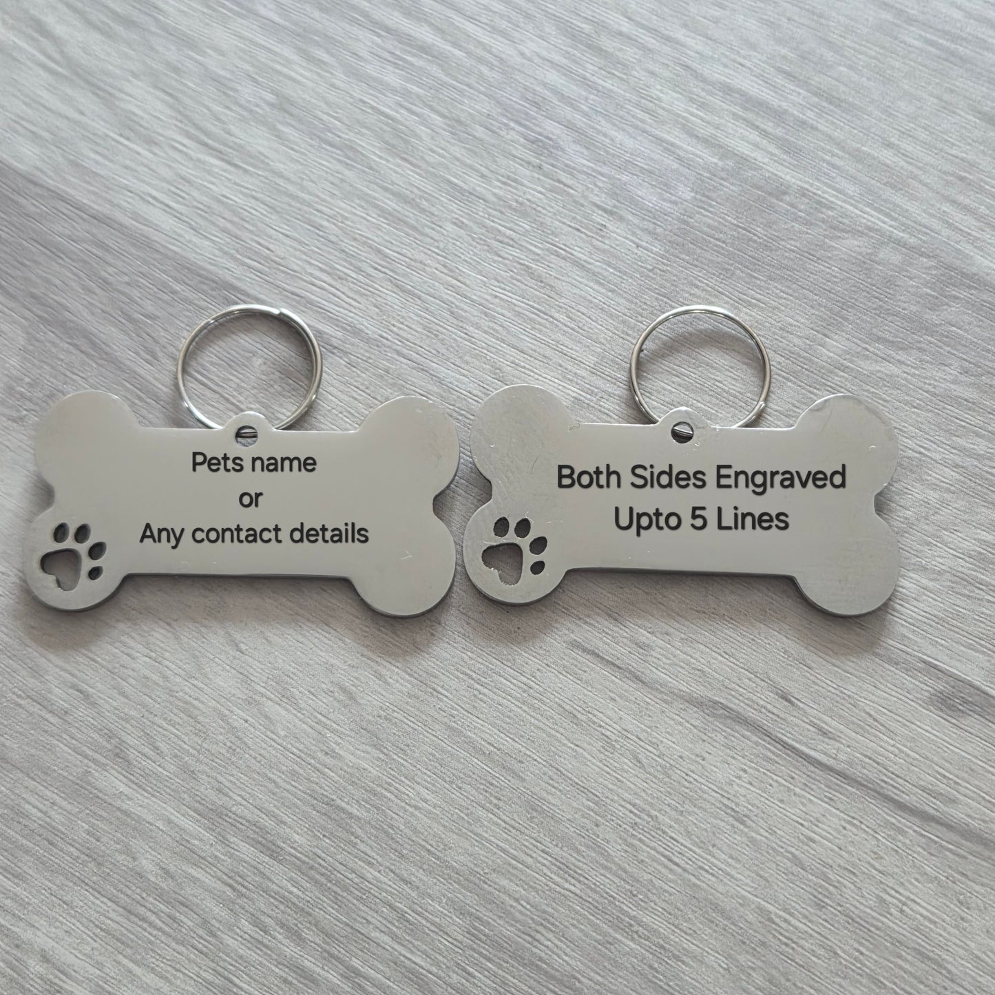 Two bone-shaped pet tags on a gray surface