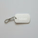 Silver dog tag with chain on a light wooden surface