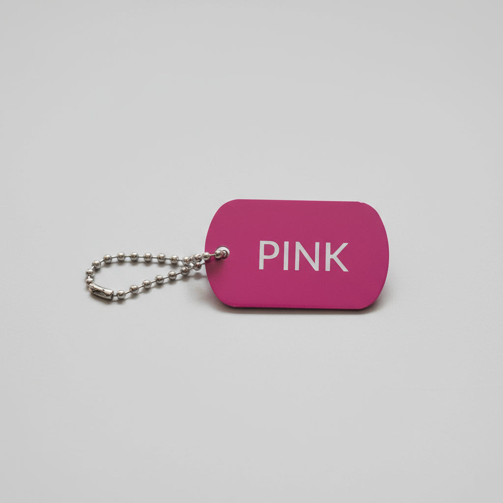 Pink keychain tag with 'PINK' text on a gray wooden surface