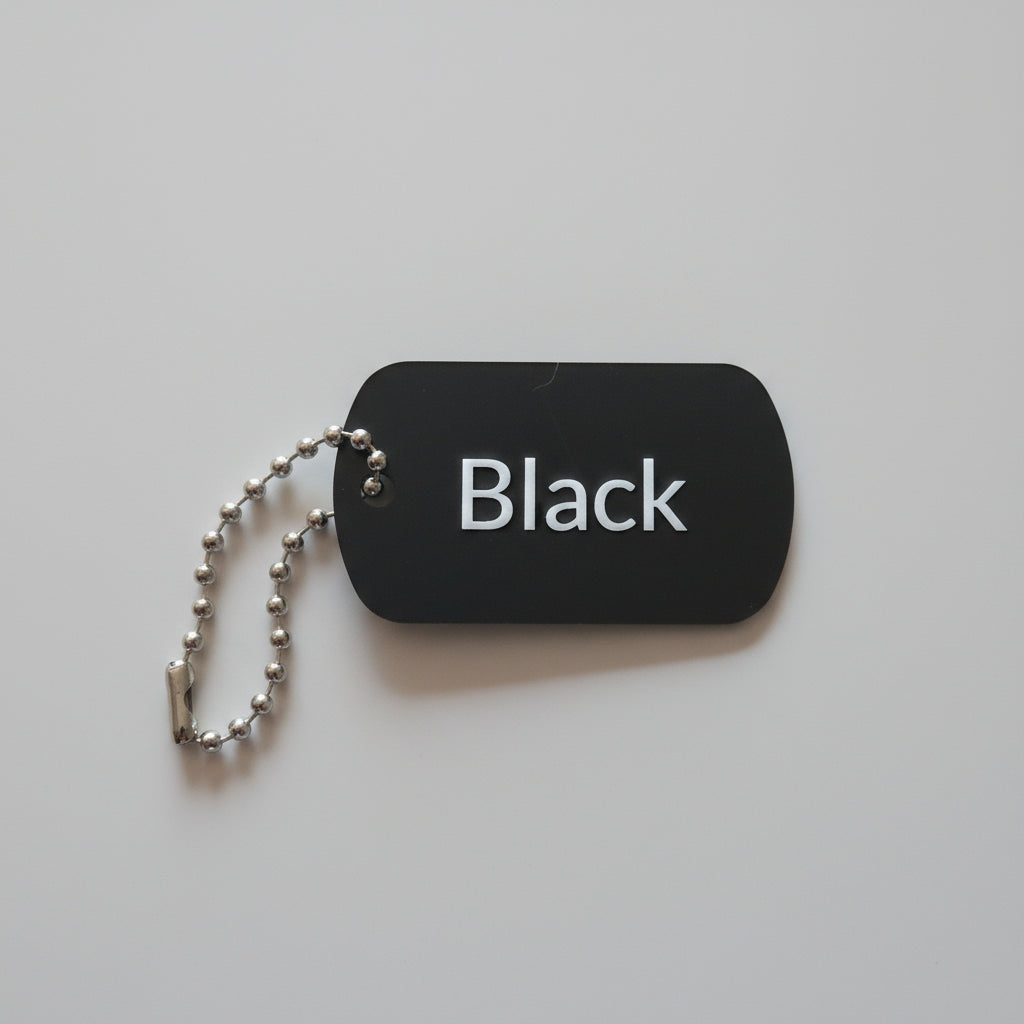 Black dog tag with 'Black' text on a light wooden surface