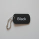 Black dog tag with 'Black' text on a light wooden surface