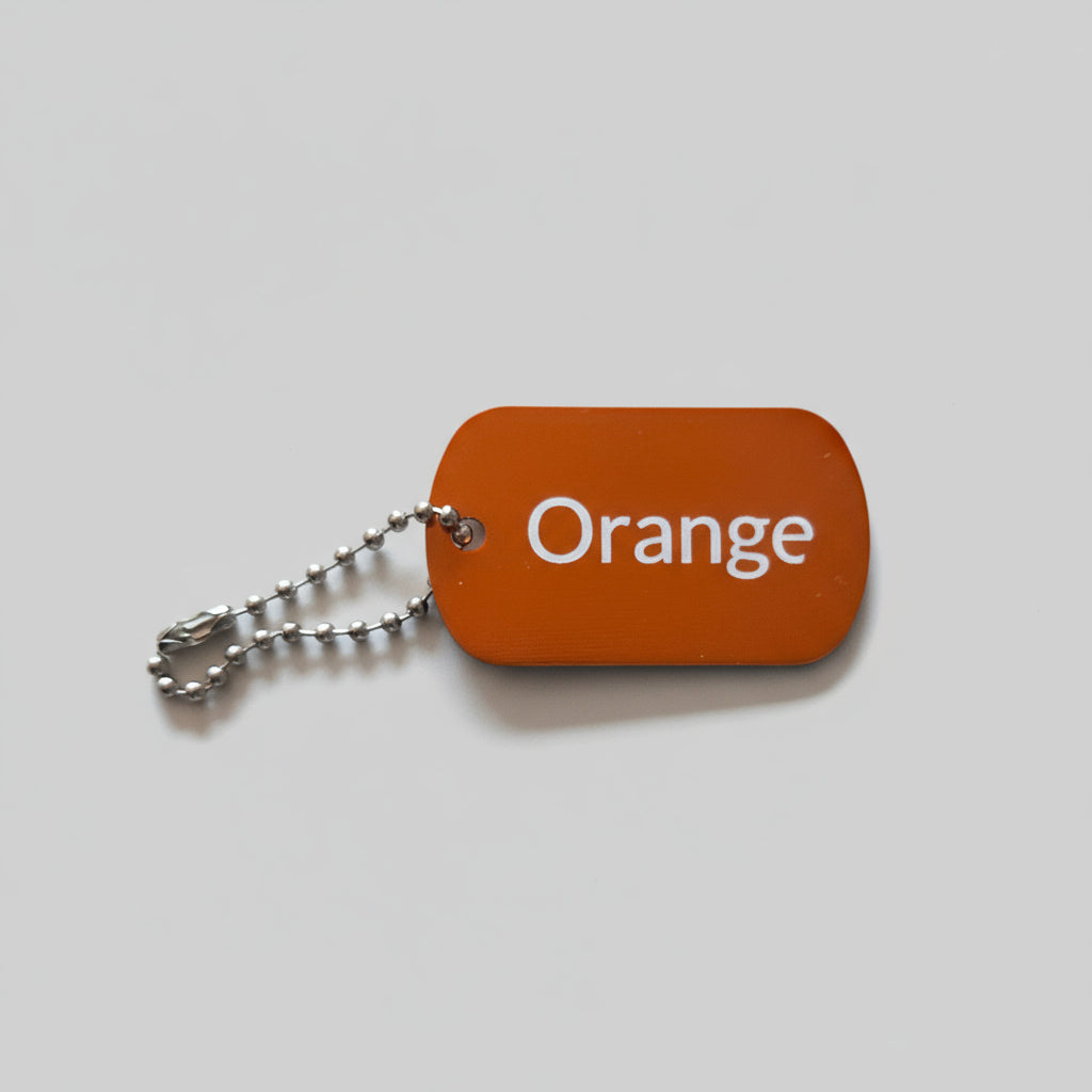 Orange color swatch keychain on a gray wooden surface