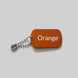 Orange color swatch keychain on a gray wooden surface