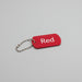 Red keychain tag with 'Red' text on a light wooden surface