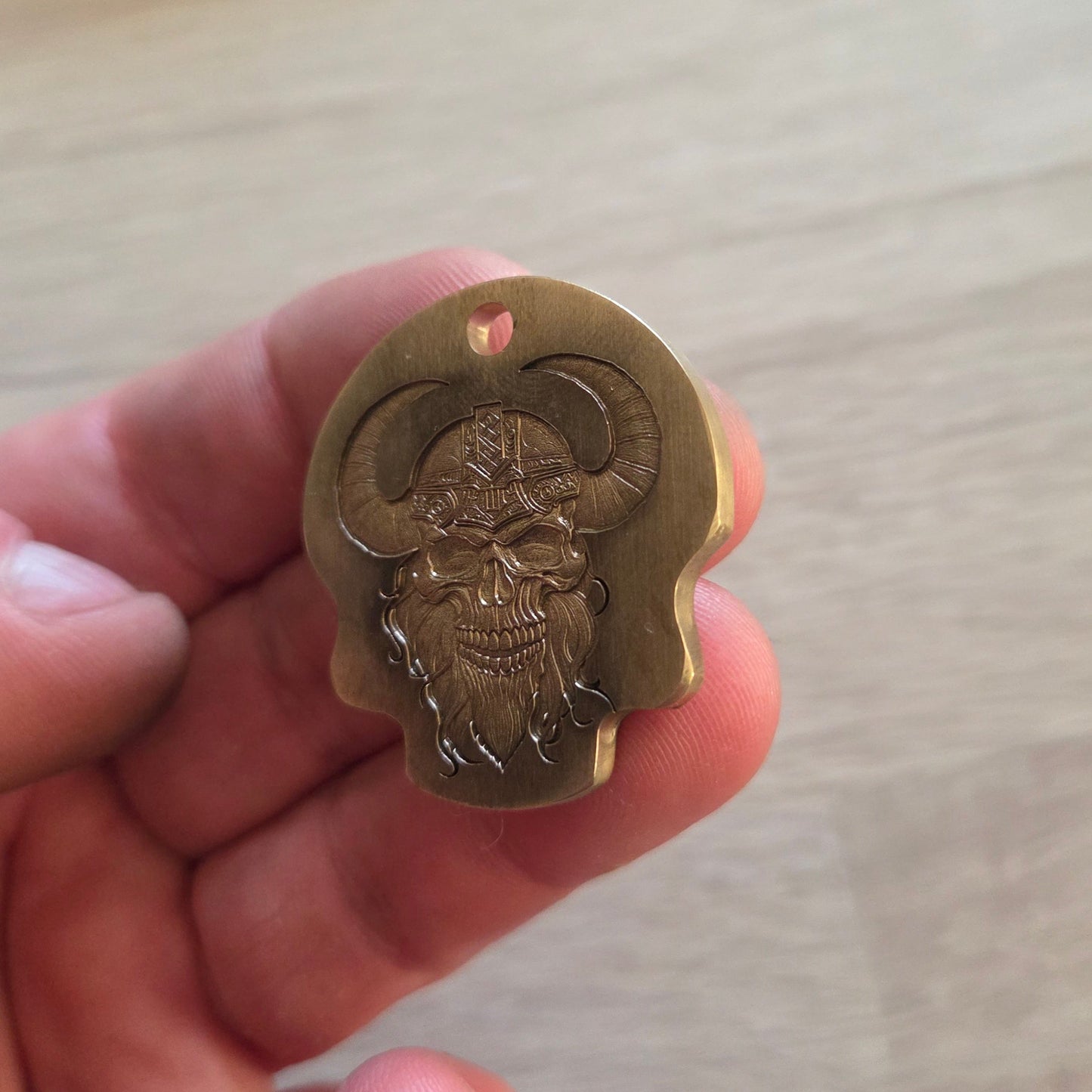 Hand holding a small brass emblem or badge against a neutral background