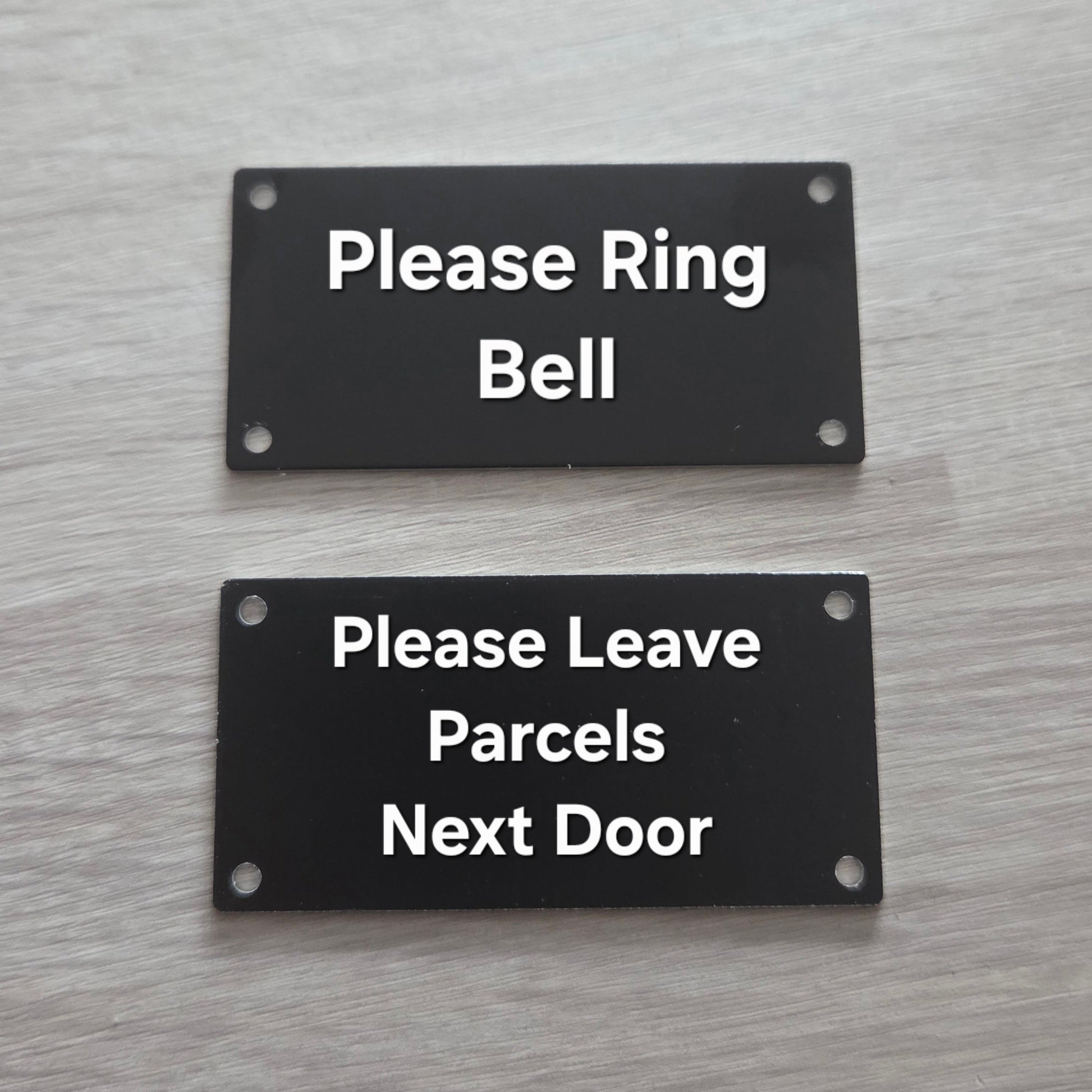 Two black signs on a door with white text.