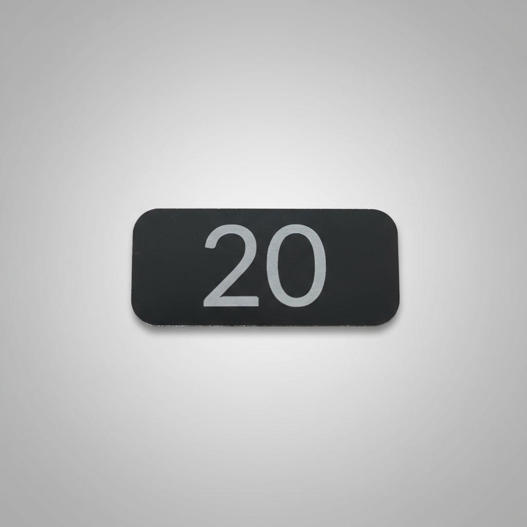 Black rectangular sign with the number 20 on a gray wooden surface