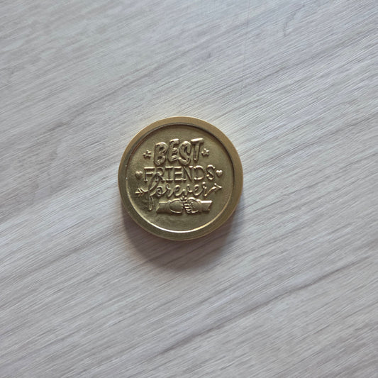Bronze coin with text on a light wooden surface
