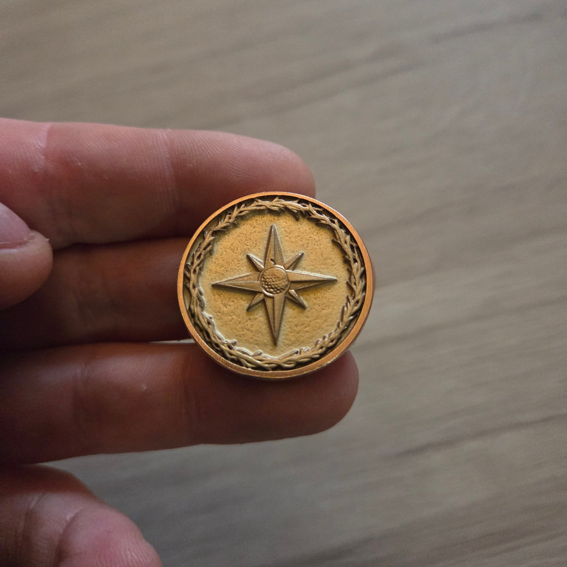 Gold medallion with star design held in a hand against a wooden background