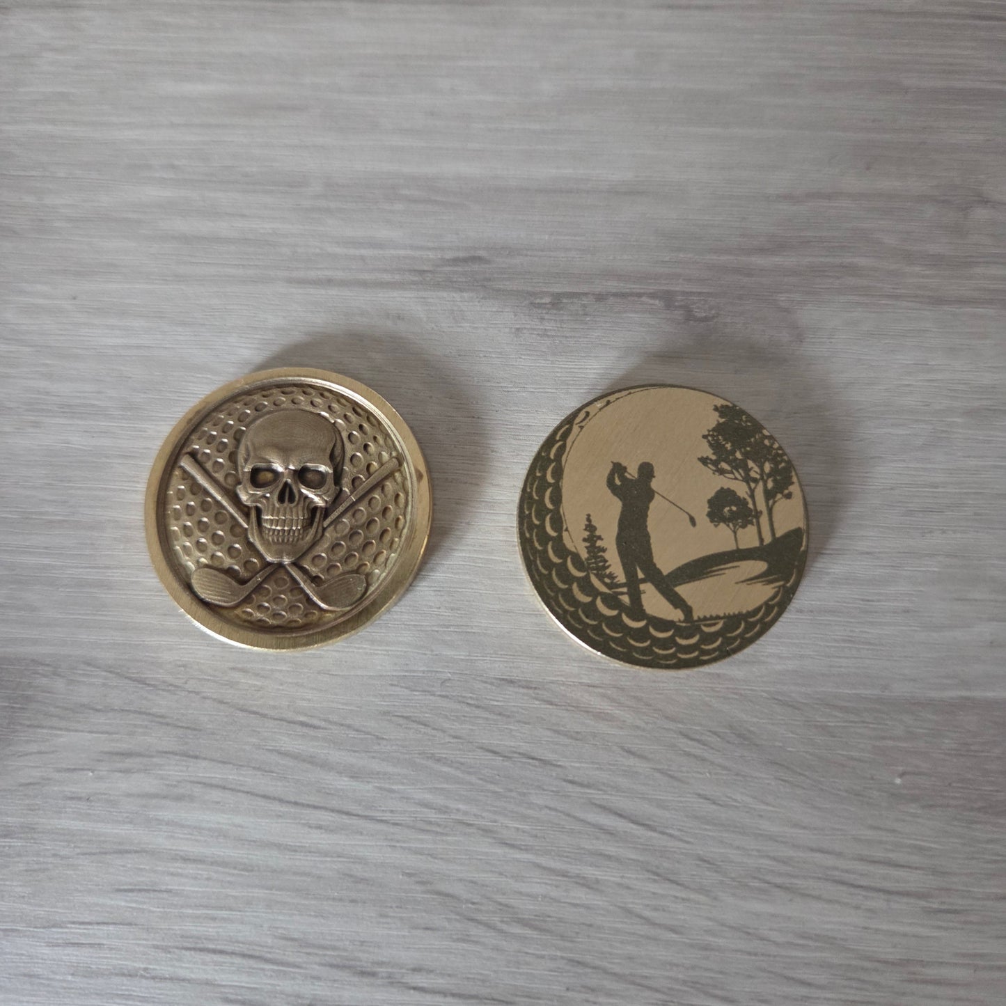 Two brass buttons with engraved designs on a wooden surface