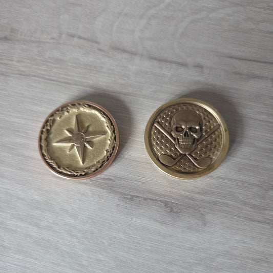 Two gold buttons with star designs on a gray wooden surface