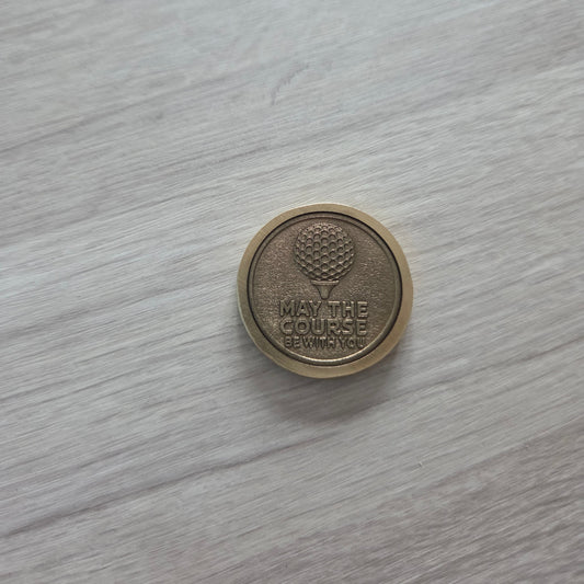 Round metallic object with embossed design on a light wooden surface