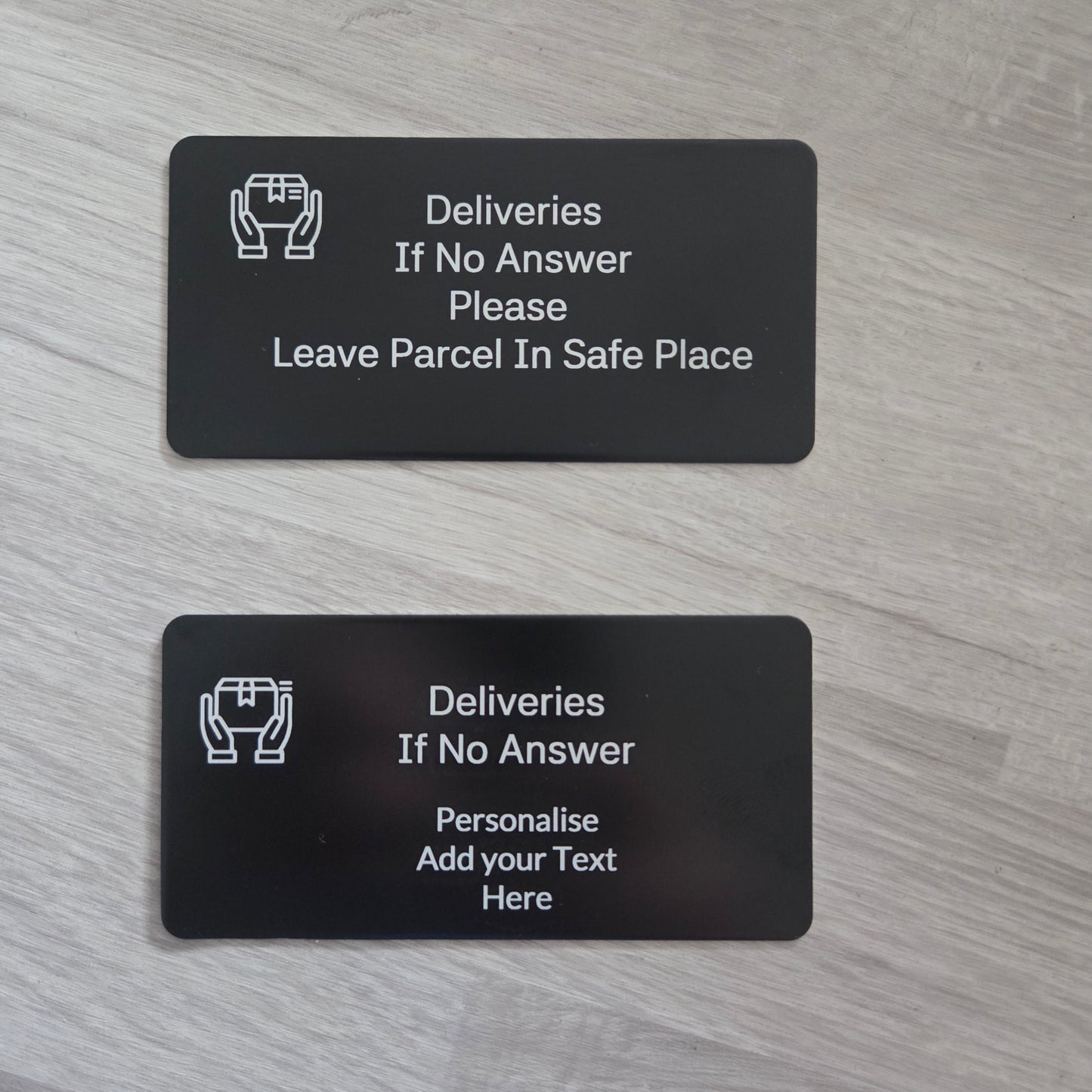 Two black plastic cards with text and icons on a gray wooden surface