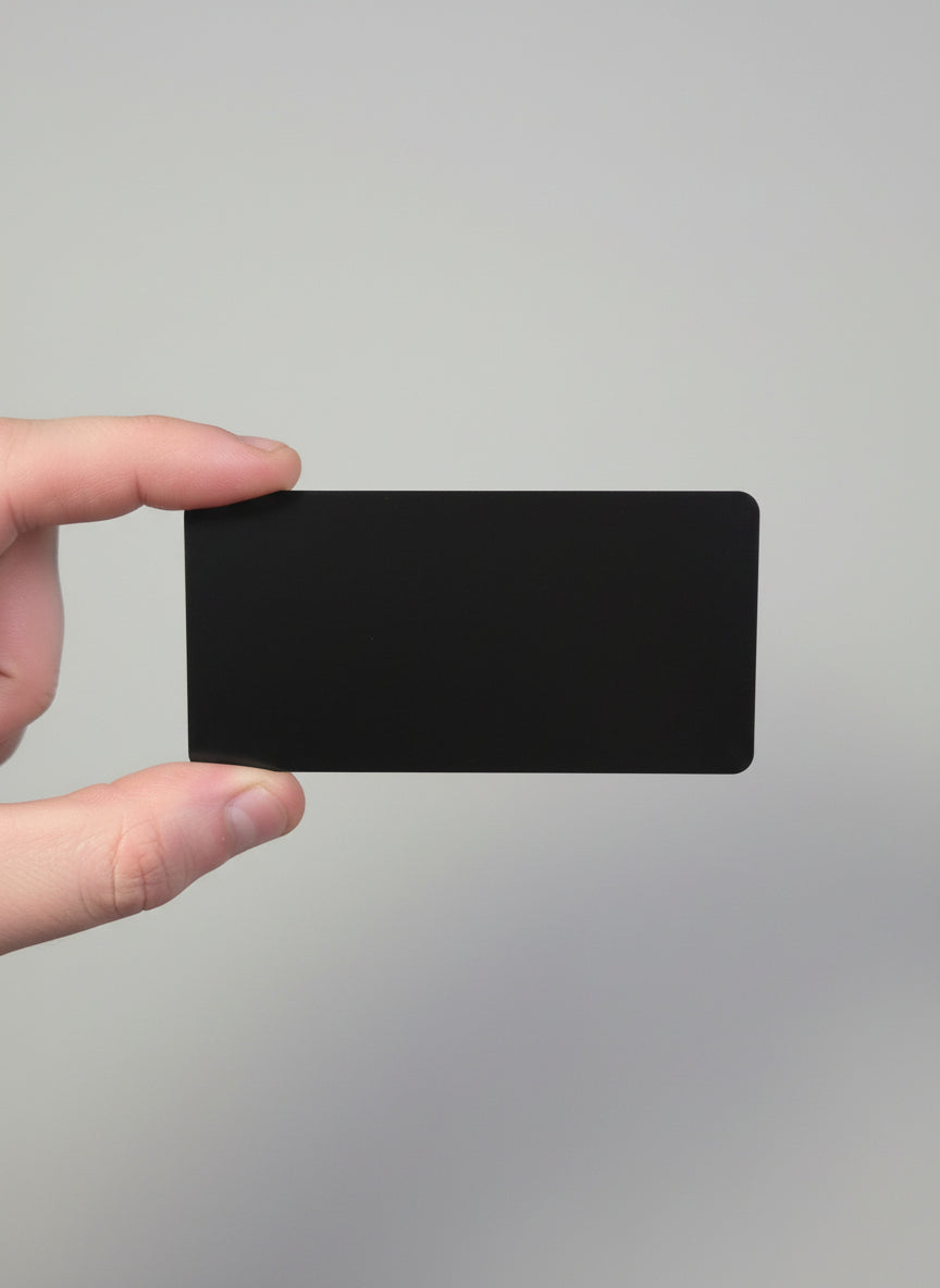 Black rectangular object held by a hand on a gray textured background