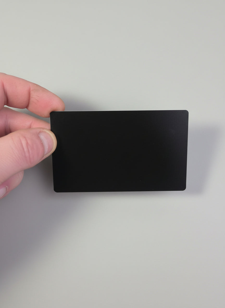 Black rectangular card held by a hand on a textured gray surface
