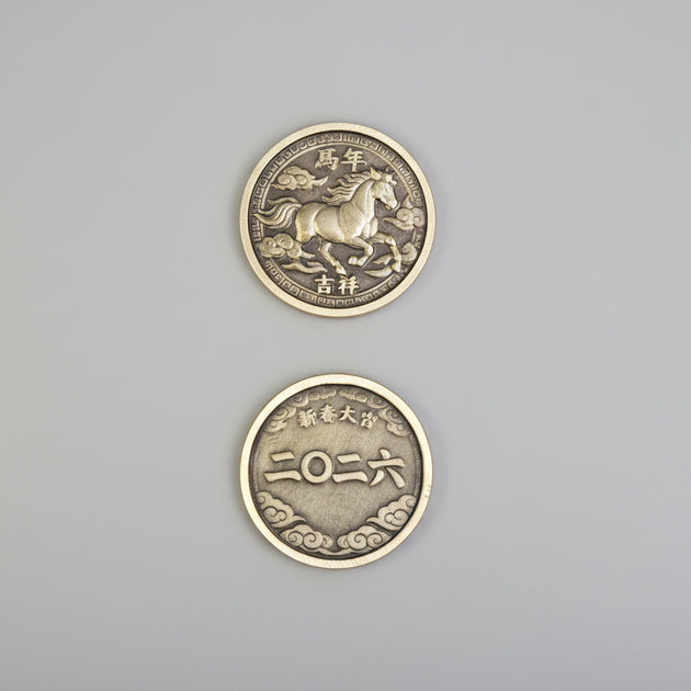 Two metallic coins with horse design and text on a textured surface